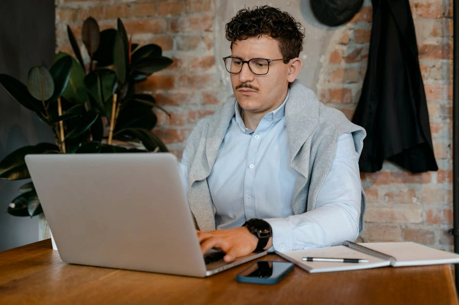 A person calmly reviewing financial documents at a wooden desk with a notebook and coffee.